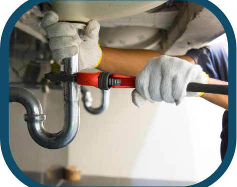 A person wearing white gloves uses a red pipe wrench to tighten or loosen a metal pipe under a sink during a Kitchen Plumbing Repair in Denver. | High 5 Plumbing, Heating & Cooling